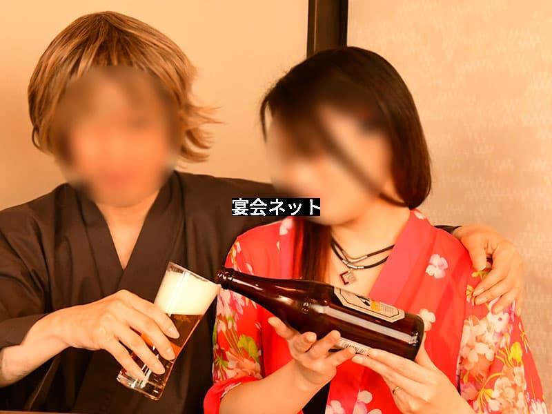 赤い浴衣を着た美女がビールを男性に注ぐ様子